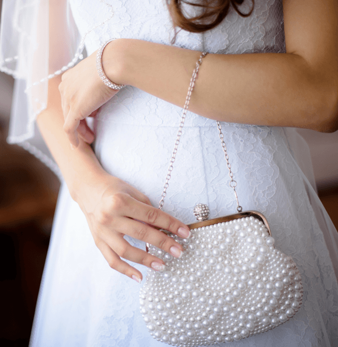 Braut mit Brauttasche und bestickten Perlen